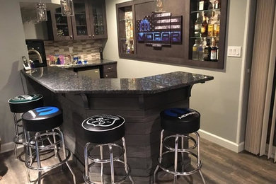 Inspiration for a mid-sized contemporary u-shaped light wood floor and brown floor seated home bar remodel in New York with an undermount sink, shaker cabinets, brown cabinets, granite countertops, multicolored backsplash and matchstick tile backsplash