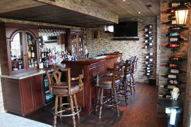 Esempio di un grande bancone bar mediterraneo con lavello da incasso, ante di vetro, ante marroni, top in granito, paraspruzzi beige, paraspruzzi con piastrelle in pietra e parquet scuro