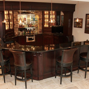 Réalisation d'un grand bar de salon avec évier tradition avec un évier encastré, un placard avec porte à panneau encastré, des portes de placard en bois sombre, un plan de travail en granite, une crédence marron, une crédence en carreau de verre et un sol en carrelage de porcelaine.