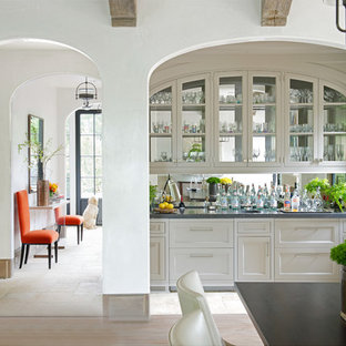 Ispirazione per un piccolo angolo bar con lavandino chic con lavello sottopiano, ante in stile shaker, ante bianche, paraspruzzi a specchio e pavimento in travertino