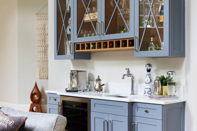 Inspiration for a cottage single-wall medium tone wood floor and brown floor home bar remodel in Boston with an undermount sink, shaker cabinets, blue cabinets and white countertops