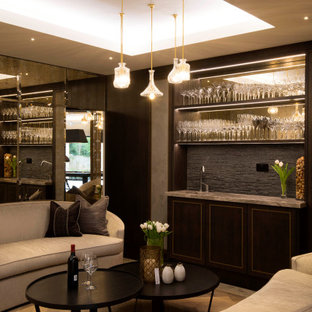 Photo of a medium sized traditional single-wall wet bar in West Midlands with an integrated sink, dark wood cabinets, onyx worktops, grey splashback, medium hardwood flooring and brown floors.