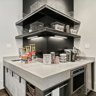 Immagine di un piccolo angolo bar con lavandino industriale con lavello sottopiano, ante lisce, ante grigie, top in quarzo composito, paraspruzzi nero, pavimento in legno verniciato, pavimento marrone e top grigio