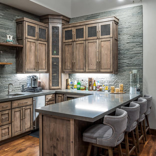 Mountain style u-shaped dark wood floor and brown floor seated home bar photo in Sacramento with an undermount sink, shaker cabinets, medium tone wood cabinets, gray backsplash and gray countertops