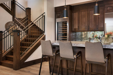 Inspiration for a large transitional galley light wood floor and brown floor wet bar remodel in Denver with an undermount sink, shaker cabinets, dark wood cabinets, quartzite countertops, gray backsplash and mirror backsplash