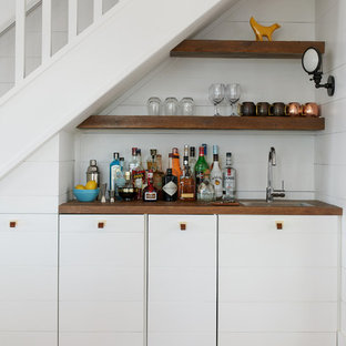 Foto de bar en casa con fregadero lineal, costero, pequeño, con encimera de madera, salpicadero blanco, suelo de madera en tonos medios, suelo marrón, encimeras marrones, armarios con paneles lisos y puertas de armario blancas