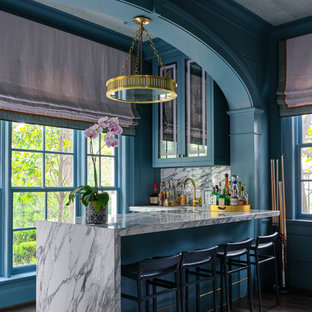 Idee per un bancone bar tradizionale con ante di vetro, ante verdi, paraspruzzi bianco, parquet scuro, pavimento marrone e top bianco