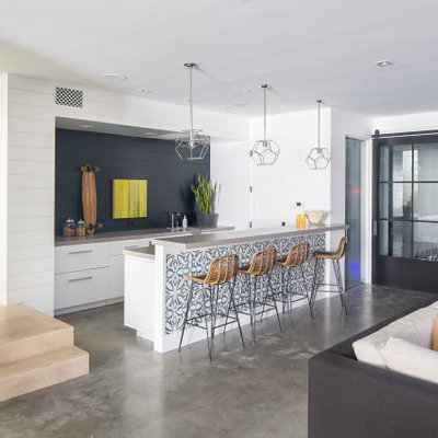 Example of a large beach style single-wall concrete floor and gray floor seated home bar design in Orange County with flat-panel cabinets, white cabinets, blue backsplash, wood backsplash and gray countertops