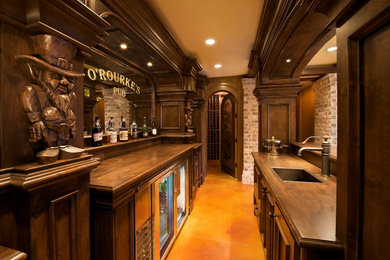 На фото: параллельный домашний бар в классическом стиле с бетонным полом, барной стойкой, накладной мойкой, фасадами с утопленной филенкой, темными деревянными фасадами, деревянной столешницей и коричневой столешницей с