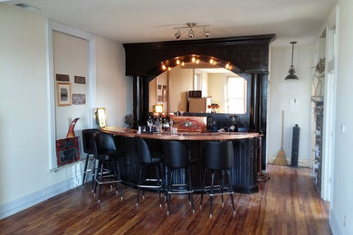 Modelo de bar en casa con fregadero en U bohemio grande con puertas de armario negras, encimera de laminado, salpicadero negro y suelo de madera clara