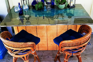 Ejemplo de bar en casa con barra de bar lineal tropical grande con encimera de vidrio, suelo de madera en tonos medios, suelo gris y encimeras azules