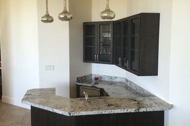 Example of a large trendy u-shaped ceramic tile seated home bar design in Other with an undermount sink, glass-front cabinets, black cabinets, granite countertops and multicolored backsplash