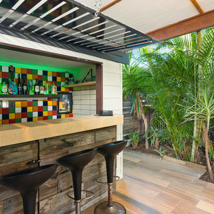 This is an example of a beach style seated home bar in Gold Coast - Tweed with multi-coloured splashback, beige floor, beige benchtop and mosaic tile splashback.