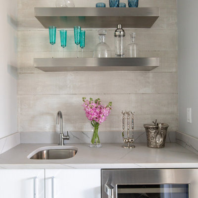 Inspiration for a small coastal single-wall wet bar remodel in Jacksonville with an undermount sink, flat-panel cabinets, white cabinets, beige backsplash and gray countertops