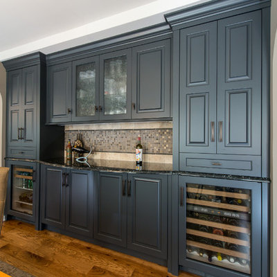 Wet bar - mid-sized contemporary single-wall medium tone wood floor and brown floor wet bar idea in Minneapolis with glass-front cabinets, gray cabinets, granite countertops, beige backsplash, stone tile backsplash and no sink