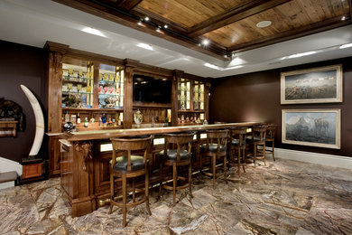 Imagen de bar en casa con barra de bar de galera clásico grande con armarios con paneles con relieve, puertas de armario de madera en tonos medios y suelo marrón
