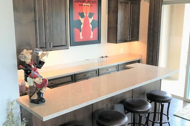 Photo of a medium sized classic u-shaped breakfast bar in Phoenix with raised-panel cabinets, dark wood cabinets, engineered stone countertops, dark hardwood flooring and brown floors.