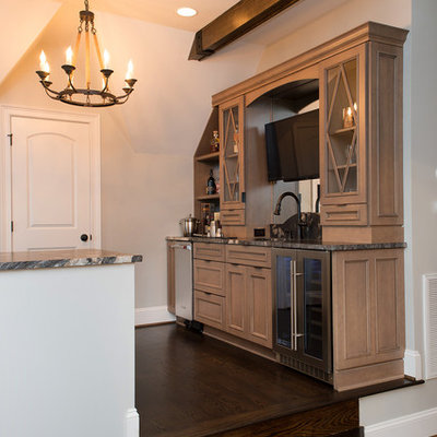 Wet bar - mid-sized rustic single-wall dark wood floor and brown floor wet bar idea in Charlotte with an undermount sink, glass-front cabinets, medium tone wood cabinets, granite countertops, mirror backsplash and brown countertops