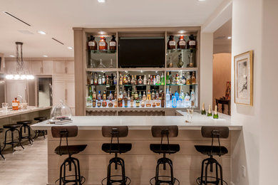 Foto di un grande bancone bar design con lavello integrato, ante lisce, ante in legno chiaro, top in cemento, paraspruzzi a specchio e parquet scuro