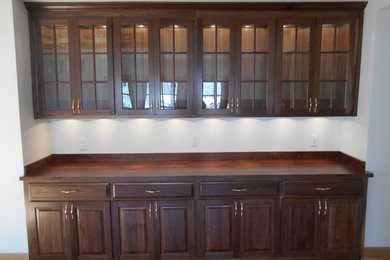 Wet bar - mid-sized traditional single-wall medium tone wood floor wet bar idea in Other with raised-panel cabinets, dark wood cabinets and wood countertops
