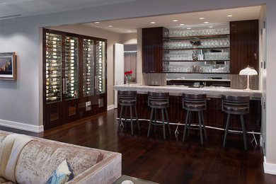 Diseño de bar en casa con barra de bar de galera actual grande con puertas de armario de madera en tonos medios, salpicadero verde, suelo de madera oscura y armarios abiertos