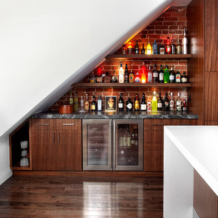 Modelo de bar en casa lineal, actual, de tamaño medio, con armarios con paneles lisos, puertas de armario de madera en tonos medios, encimera de mármol, suelo de madera oscura, salpicadero de ladrillos y salpicadero rojo