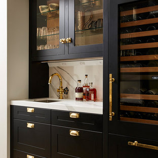 Foto di un angolo bar con lavandino chic con lavello sottopiano, ante in stile shaker, ante nere, top in quarzo composito, paraspruzzi bianco, paraspruzzi in lastra di pietra, parquet chiaro e top bianco