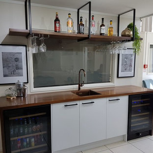 Example of a huge minimalist single-wall wet bar design in Other with an undermount sink, white cabinets and wood countertops