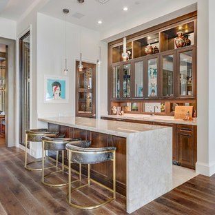 Wet bar - huge transitional single-wall medium tone wood floor and brown floor wet bar idea in Miami with medium tone wood cabinets, marble countertops, an undermount sink, recessed-panel cabinets, mirror backsplash and beige countertops