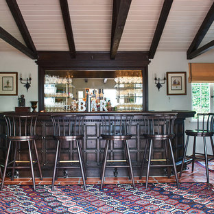 Immagine di un grande bancone bar mediterraneo con ante in legno bruno, paraspruzzi a specchio, pavimento in terracotta e pavimento arancione