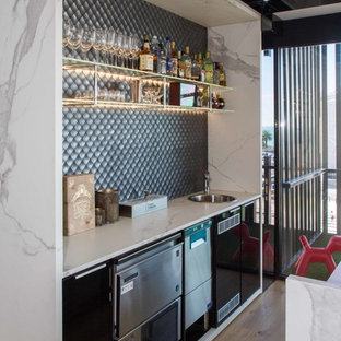 Idee per un grande bancone bar minimalista con ante lisce, lavello da incasso, ante nere, top piastrellato, paraspruzzi grigio, paraspruzzi con piastrelle a mosaico, pavimento in legno massello medio, pavimento marrone e top bianco