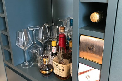 Design ideas for a small contemporary single-wall wet bar in London with flat-panel cabinets, blue cabinets, light hardwood flooring and brown floors.