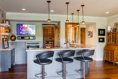 Example of a mid-sized transitional u-shaped medium tone wood floor seated home bar design in St Louis with an undermount sink, flat-panel cabinets, gray cabinets, solid surface countertops and multicolored backsplash