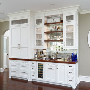 Ispirazione per un angolo bar con lavandino chic di medie dimensioni con lavello sottopiano, ante di vetro, ante bianche, top in legno, paraspruzzi a specchio, parquet scuro, pavimento marrone e top marrone