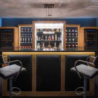 This is an example of a contemporary galley breakfast bar in London with glass-front cabinets, medium wood cabinets, carpet, black floors and black worktops.