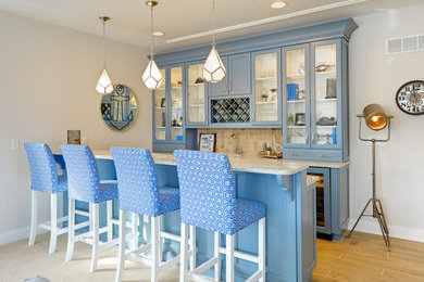 Example of a beach style galley seated home bar design in Other with glass-front cabinets, blue cabinets and beige backsplash