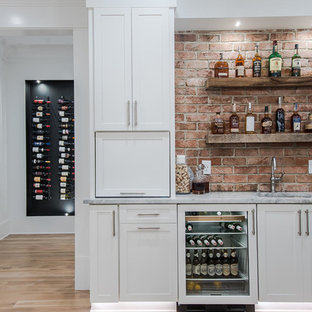 Esempio di un angolo bar con lavandino country di medie dimensioni con lavello sottopiano, ante in stile shaker, ante bianche, top in marmo, paraspruzzi rosso, paraspruzzi in mattoni, parquet chiaro e pavimento beige