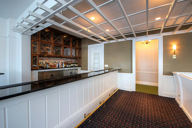 Einzeilige, Mittelgroße Klassische Hausbar mit Bartresen, Glasfronten, dunklen Holzschränken, Teppichboden und schwarzem Boden in Sonstige