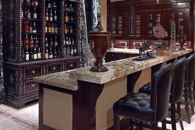 Aménagement d'un bar de salon classique en L et bois foncé avec moquette, des tabourets et un placard à porte vitrée.
