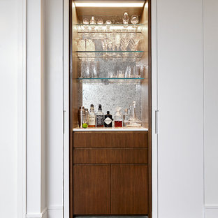Imagen de bar en casa lineal, contemporáneo, pequeño, sin pila, con armarios con paneles lisos, encimera de cuarzo compacto, salpicadero con efecto espejo, suelo de madera clara, suelo gris y puertas de armario de madera oscura