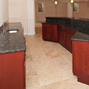 Inspiration pour un très grand bar de salon traditionnel avec des tabourets, un évier encastré, un placard avec porte à panneau surélevé, des portes de placard en bois sombre, un plan de travail en granite et un sol en marbre.
