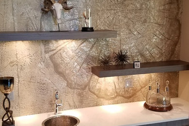 Mid-sized elegant single-wall brown floor wet bar photo in Denver with a drop-in sink, black cabinets, solid surface countertops, multicolored backsplash and white countertops
