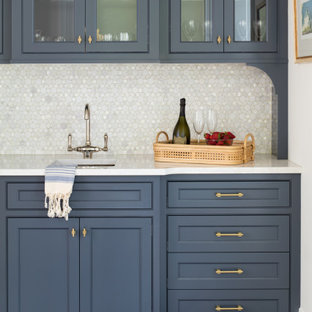 Imagen de bar en casa con fregadero lineal, costero, de tamaño medio, con fregadero bajoencimera, armarios con rebordes decorativos, puertas de armario azules, encimera de cuarcita, salpicadero blanco, salpicadero con mosaicos de azulejos, suelo de madera en tonos medios, suelo marrón y encimeras blancas