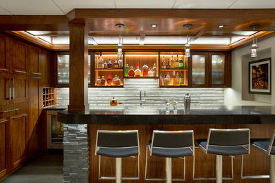 Example of a large transitional galley seated home bar design in Boston with solid surface countertops, open cabinets, medium tone wood cabinets, gray backsplash and stone tile backsplash