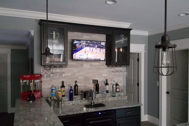 Seated home bar - mid-sized modern l-shaped ceramic tile seated home bar idea in Indianapolis with a drop-in sink, glass-front cabinets, dark wood cabinets, granite countertops, multicolored backsplash and ceramic backsplash