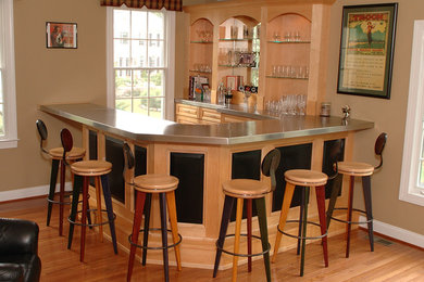 Inspiration for a mid-sized contemporary u-shaped light wood floor and brown floor seated home bar remodel in Philadelphia with raised-panel cabinets, light wood cabinets and stainless steel countertops