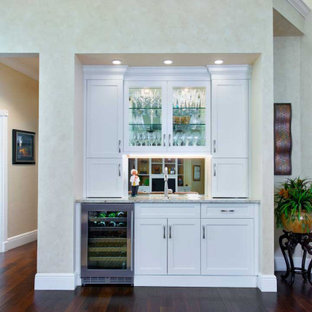 Foto di un piccolo angolo bar con lavandino chic con lavello sottopiano, ante in stile shaker, ante bianche, top in granito, paraspruzzi a specchio, parquet scuro, pavimento marrone e top beige