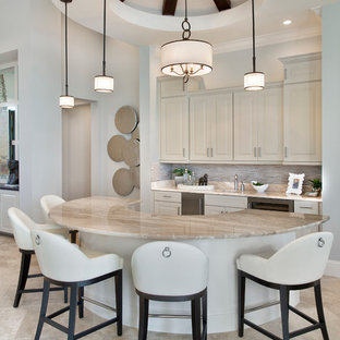Modelo de bar en casa con barra de bar clásico con fregadero bajoencimera, armarios con paneles con relieve, puertas de armario beige, salpicadero multicolor y suelo beige