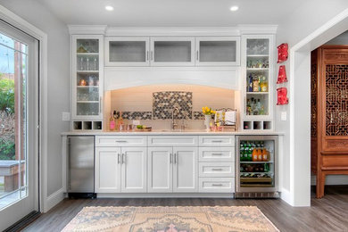 Inspiration for a small transitional single-wall dark wood floor and brown floor wet bar remodel in San Francisco with an undermount sink, white cabinets, white backsplash, subway tile backsplash, white countertops and recessed-panel cabinets