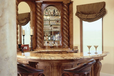 Foto de bar en casa con barra de bar en U tradicional con armarios con paneles empotrados, puertas de armario de madera en tonos medios y suelo beige